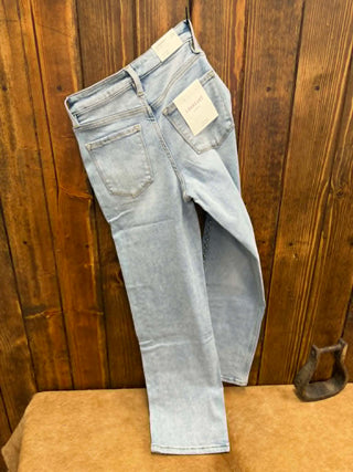 Light blue jeans on a brown stool against a wooden wall