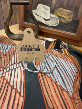 Silver hoop earrings on a 'Lucky J' branded card with a rustic background.