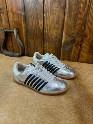White sneakers with black stripes on a wooden floor