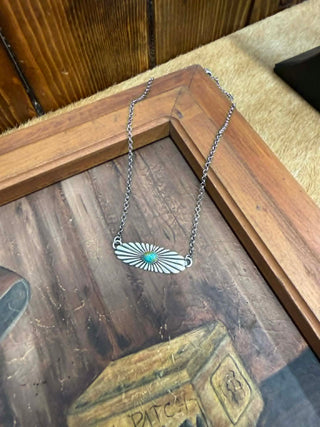 Silver necklace with a turquoise pendant on a wooden surface