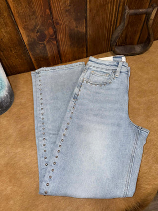 Folded light blue jeans with decorative studs on a wooden surface