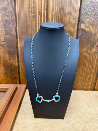 Necklace with turquoise beads on a black mannequin against a wooden background