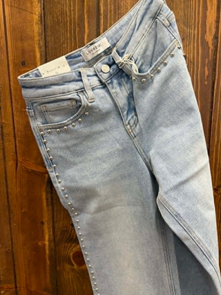 Light blue jeans with studded details on a wooden surface