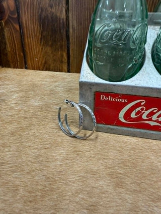 Sterling Silver hoop earrings on a wooden surface with a Coca-Cola sign in the background