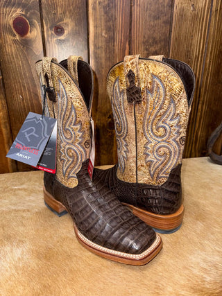 Chocolate Caiman Belly Boots with a square toe and decorative stitching on a wooden surface.