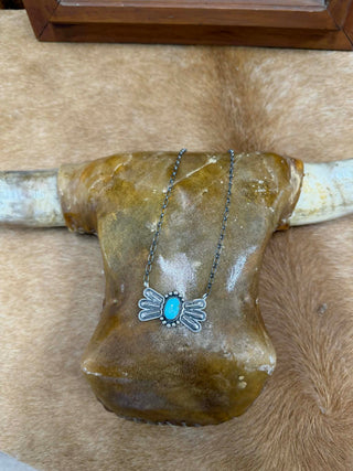 Necklace with a blue pendant on a wooden surface