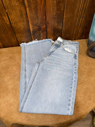 Folded light blue jeans on a wooden surface with a wooden panel background