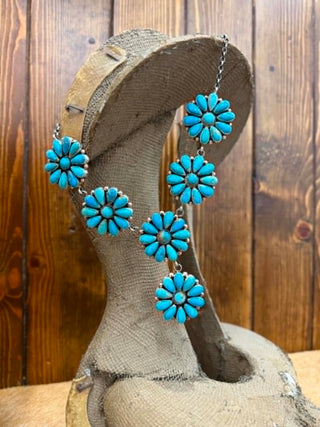 Turquoise flower-shaped jewelry set on a wooden stand