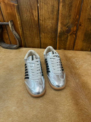 Silver sneakers with black stripes on a wooden floor