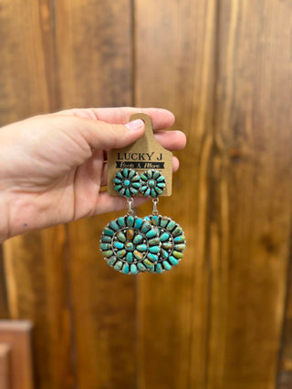 Turquoise earrings on a wooden stand with a wooden background