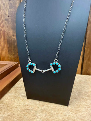 Necklace with turquoise stones on a black stand against a wooden background