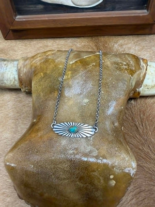 Silver necklace with a turquoise stone pendant on a rock