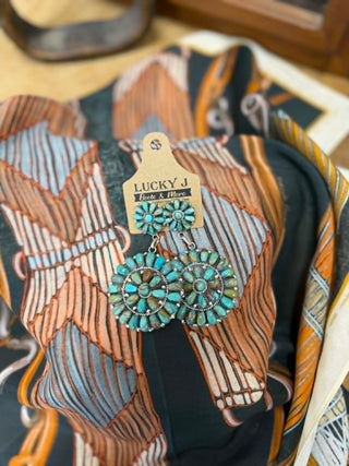 Turquoise earrings on a patterned fabric background