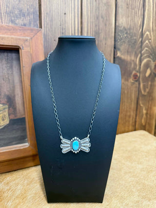 Necklace with a dragonfly design on a black bust against a wooden background