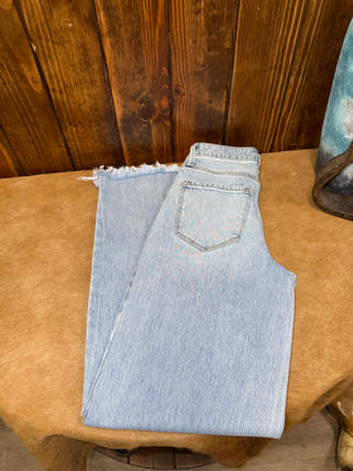 Light blue jeans folded on a wooden surface with a wooden panel background