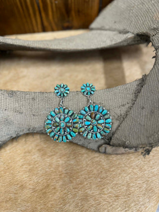 Turquoise and silver earrings on a textured surface